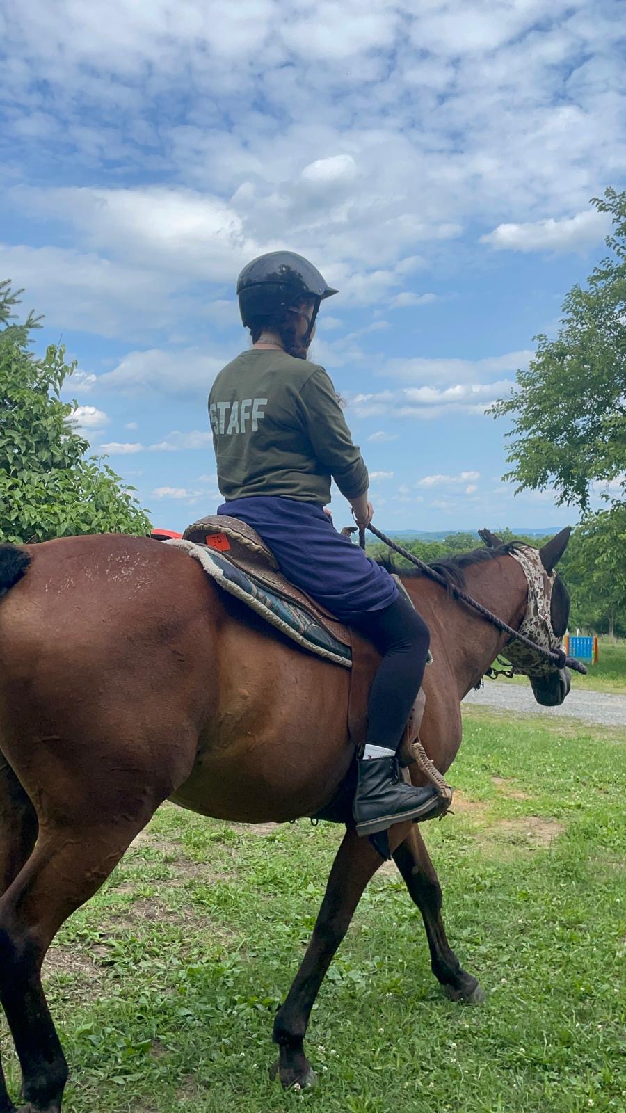 Staff member riding a horse through the farm field